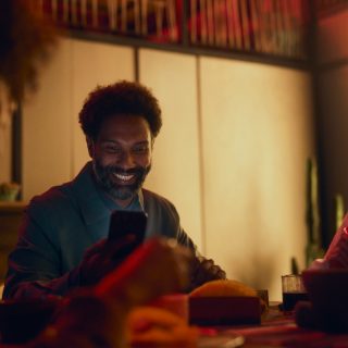 Un hombre sonriente comprueba el sistema de seguridad para el hogar inteligente en su smartphone