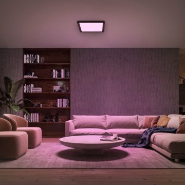 Black square LED ceiling panel shining purple light in living room