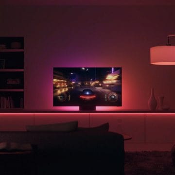 Téléviseur diffusant un jeu de course dans le salon avec des lumières roses et rouges