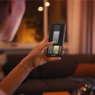 Une personne qui contrôle l’éclairage intelligent Philips Hue à l’aide de l’application Hue sur un téléphone intelligent.