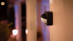 Un capteur extérieur Philips Hue monté sur un poteau en bois dans un jardin