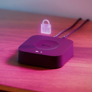 Un nouveau système de contrôle d'éclairage intérieur Hue Bridge Pro en noir, posé sur une table et comportant un symbole de cadenas pour la sécurité Zigbee.