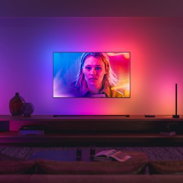 Een tv gesynchroniseerd met Philips Hue surroundverlichting in blauwe, roze en rode tinten, die overeenkomt met de actie op het scherm.