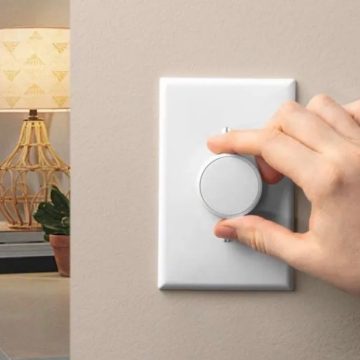 Hand die aan de knop draait van een witte slimme lichtschakelaar op de muur