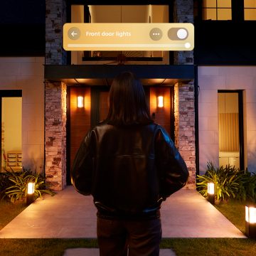 En person nærmer seg inngangsdøra til et hjem og utløser Philips Hue lys via en Video Doorbell.