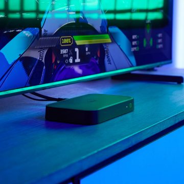 En HDMI Sync box 8K som står på et TV-bord i et rom med blå underholdningsbelysning.