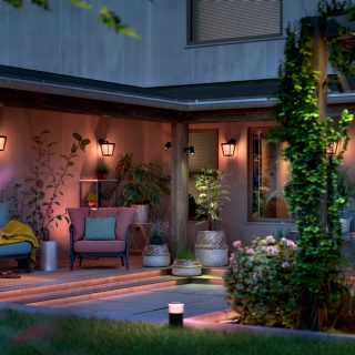 A backyard patio lit with Philips Hue outdoor smart lighting glowing in warm white and pink tones