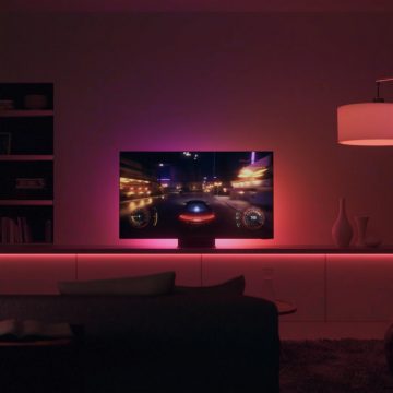 Televizor în camera de zi, pe care este redat un joc de curse, cu lumini roze și roșii